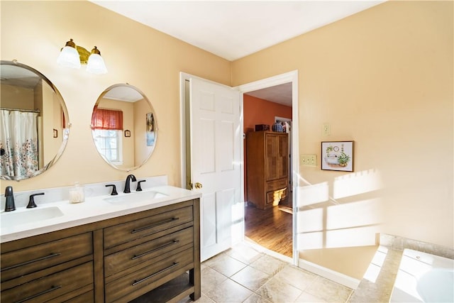 full bathroom with double vanity, tile patterned flooring, a tub, and a sink