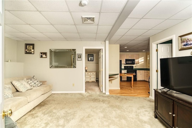 living room with baseboards, visible vents, a drop ceiling, and light carpet