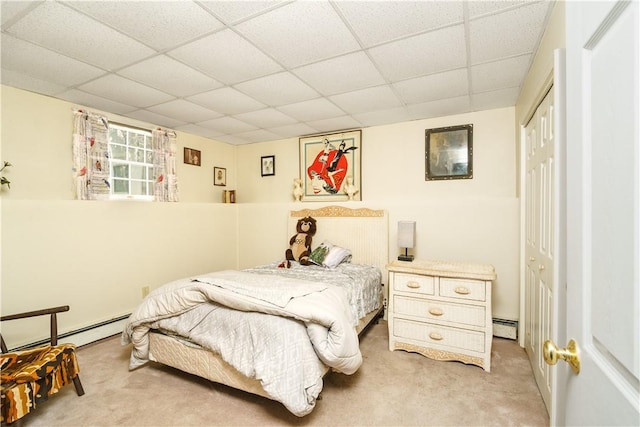 carpeted bedroom with a closet, a paneled ceiling, and a baseboard radiator