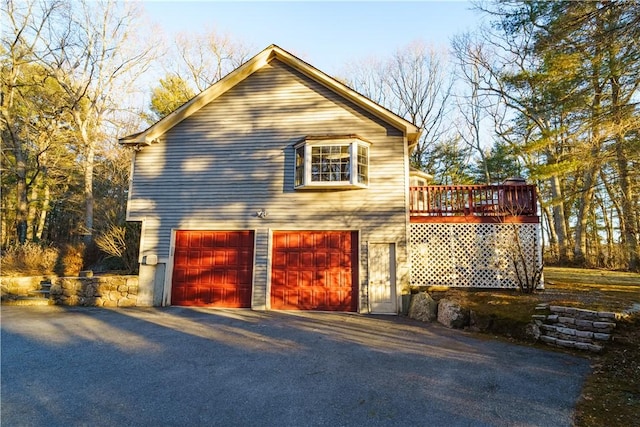 view of side of home featuring an attached garage, a wooden deck, and driveway