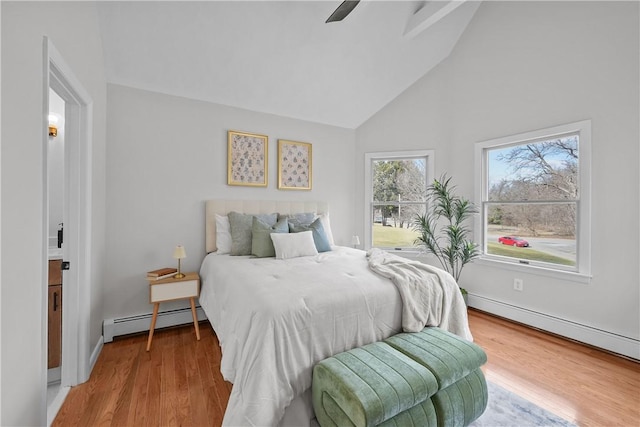 bedroom featuring a baseboard heating unit, baseboards, high vaulted ceiling, and wood finished floors