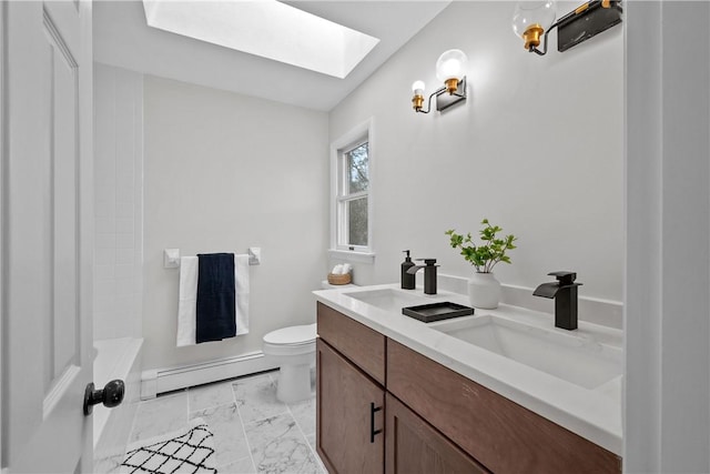 bathroom with toilet, a sink, a skylight, double vanity, and baseboard heating