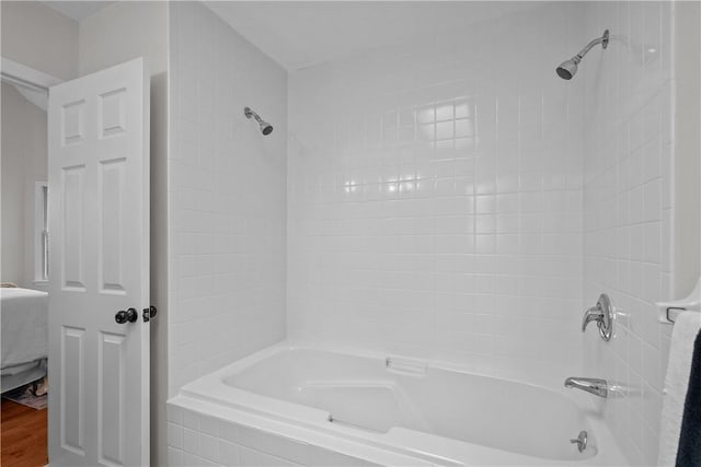 ensuite bathroom featuring connected bathroom, bathing tub / shower combination, and wood finished floors