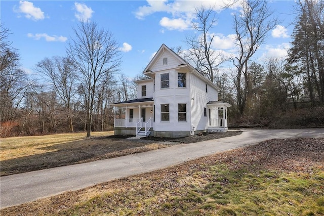 victorian-style house with a porch and driveway