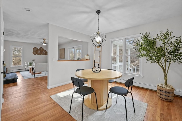 dining room with a baseboard heating unit, light wood-style flooring, baseboards, and a chandelier