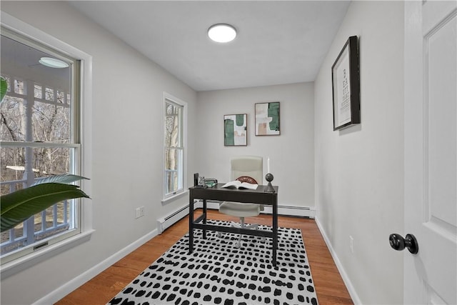 home office with a baseboard heating unit, baseboards, and wood finished floors