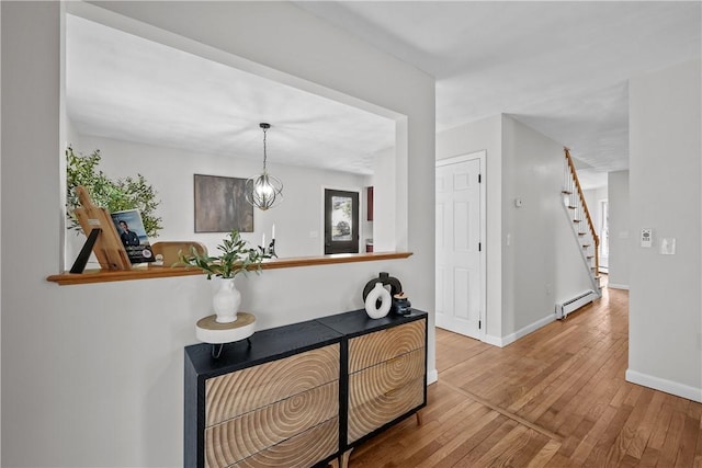 hall featuring baseboard heating, stairway, baseboards, and hardwood / wood-style floors