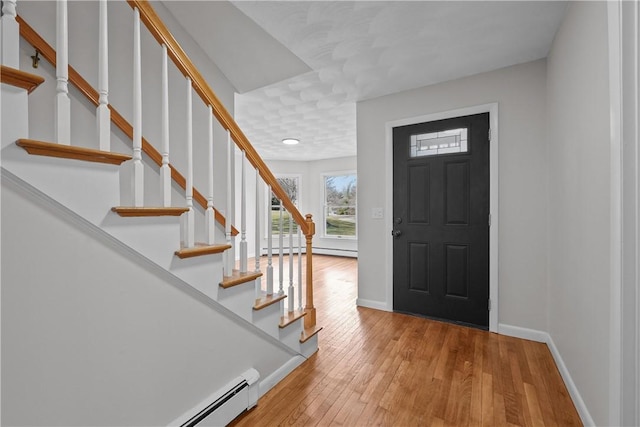 entrance foyer featuring light wood-type flooring, baseboards, baseboard heating, and a baseboard heating unit