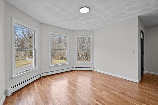 empty room with light wood-style flooring, baseboards, and a baseboard radiator