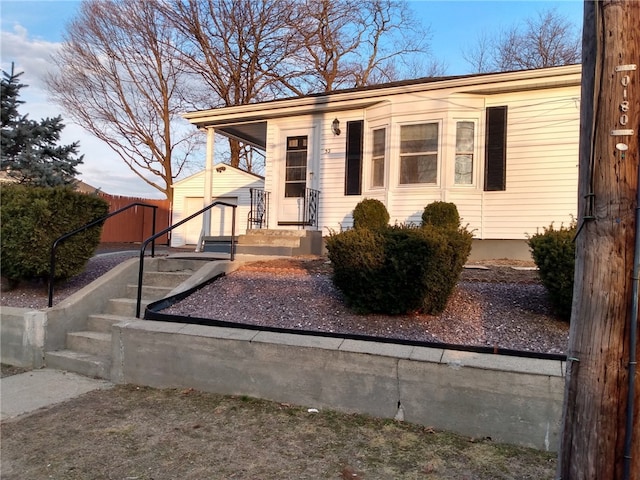 view of front of home with an outdoor structure, a storage unit, and fence