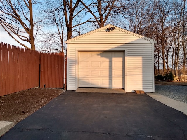 detached garage featuring fence and driveway