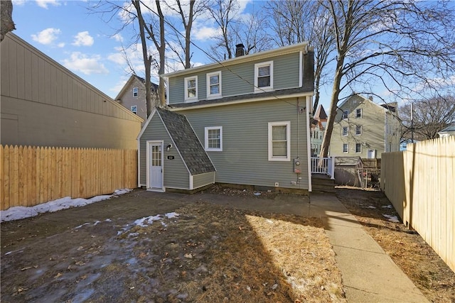 rear view of property with a storage shed, an outdoor structure, and a fenced backyard