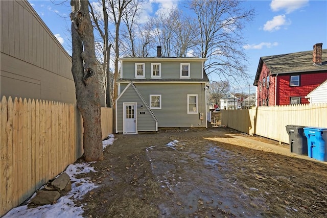 rear view of house featuring a chimney and fence