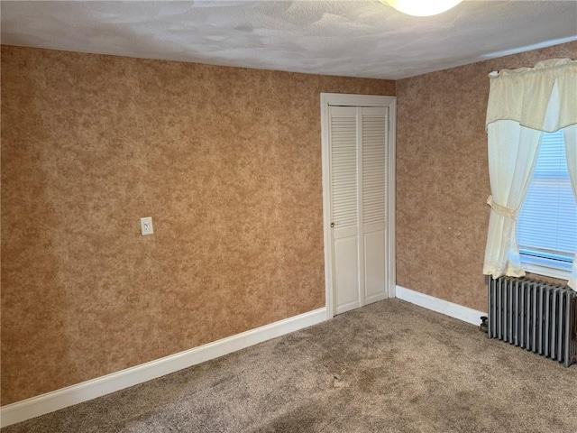 unfurnished bedroom featuring carpet flooring, baseboards, a closet, and radiator heating unit