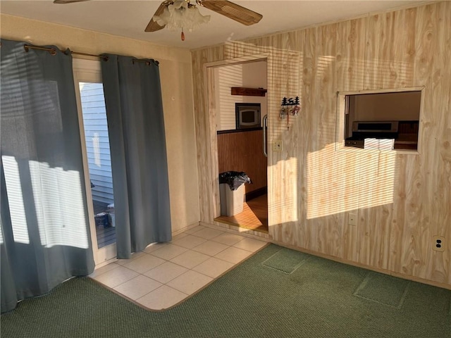 interior space with carpet, ceiling fan, and wood walls