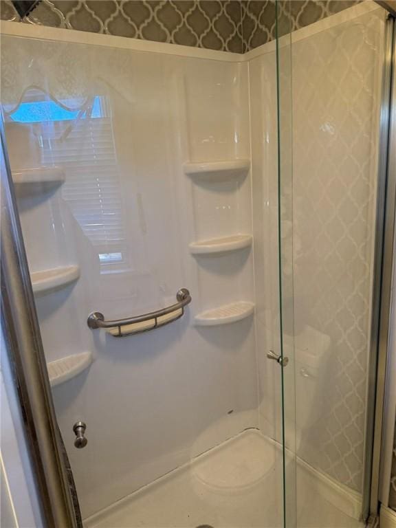 bathroom featuring a stall shower and wallpapered walls