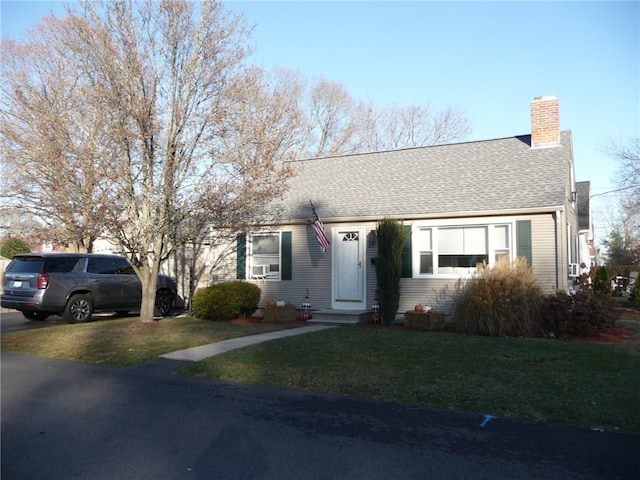 view of front of home with a front lawn, a chimney, and a shingled roof