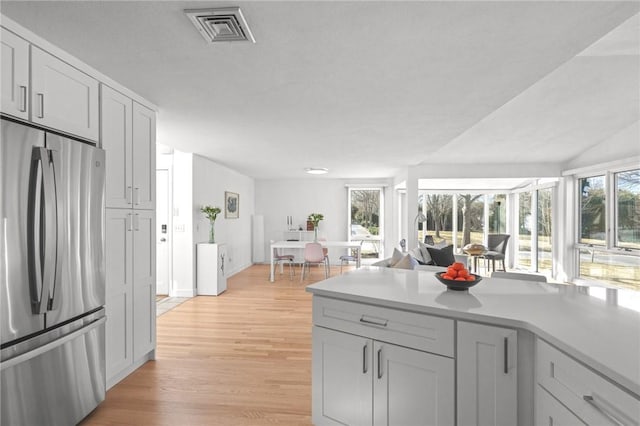 kitchen with light wood finished floors, a healthy amount of sunlight, visible vents, and freestanding refrigerator