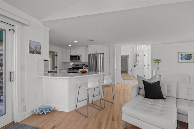 kitchen featuring light wood-type flooring, light countertops, a peninsula, white cabinets, and stainless steel appliances