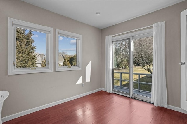 spare room featuring baseboards and wood finished floors