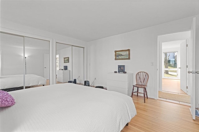 bedroom featuring light wood-type flooring and multiple closets