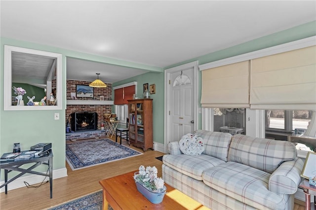 living area with a fireplace, baseboards, and wood finished floors