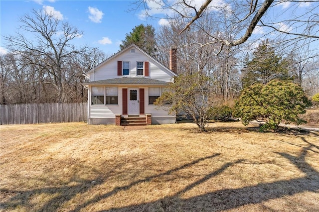 view of front of home featuring entry steps, a chimney, a front lawn, and fence