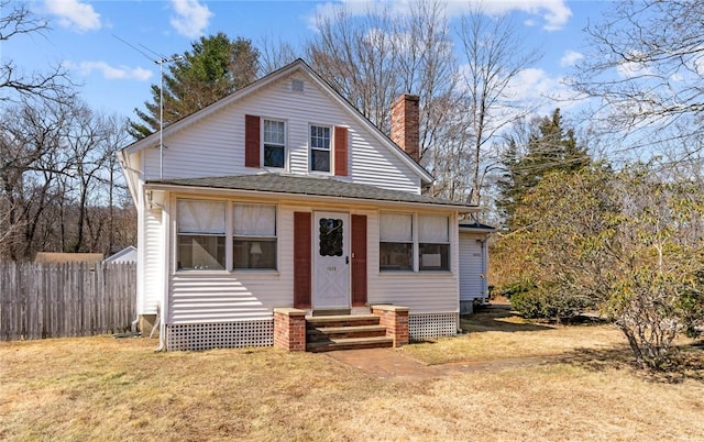 view of front of home featuring fence, entry steps, roof with shingles, a front yard, and a chimney