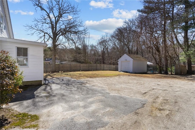 view of yard with a garage, driveway, an outdoor structure, and fence