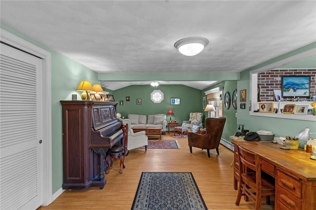 living area with vaulted ceiling, wood finished floors, baseboards, and a baseboard radiator