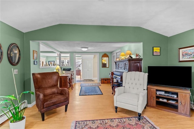 living area with baseboards, lofted ceiling, and wood finished floors