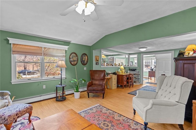 living area with a baseboard heating unit, wood finished floors, a ceiling fan, and vaulted ceiling