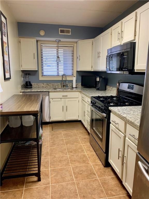 kitchen featuring light tile patterned floors, visible vents, a sink, stainless steel appliances, and white cabinetry