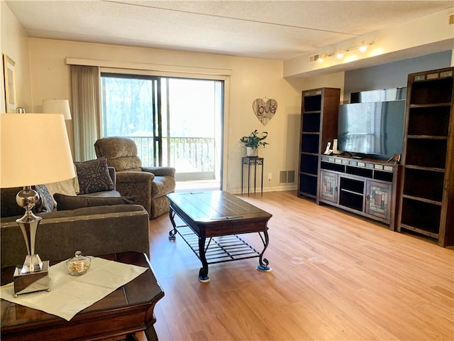 living room featuring visible vents, baseboards, and wood finished floors