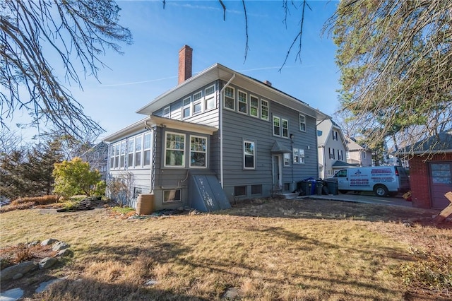 rear view of house featuring a yard and a chimney