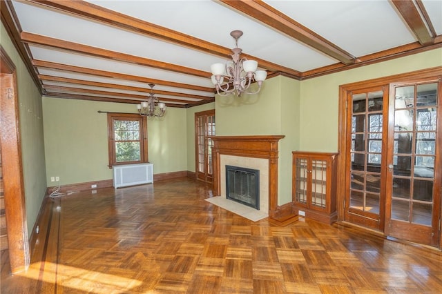 unfurnished living room featuring radiator, baseboards, a premium fireplace, beam ceiling, and an inviting chandelier