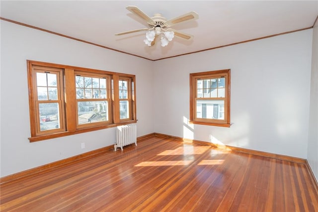 unfurnished room with ornamental molding, radiator, baseboards, and wood finished floors