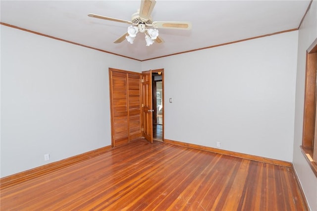 unfurnished room with crown molding, wood finished floors, baseboards, and ceiling fan