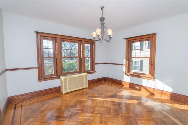 spare room with baseboards, radiator, and an inviting chandelier