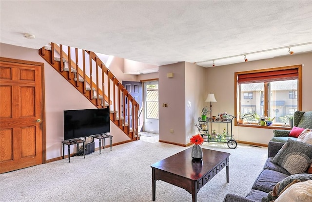 carpeted living area featuring stairway, track lighting, and baseboards