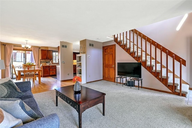 living room featuring stairs, baseboards, visible vents, and a chandelier