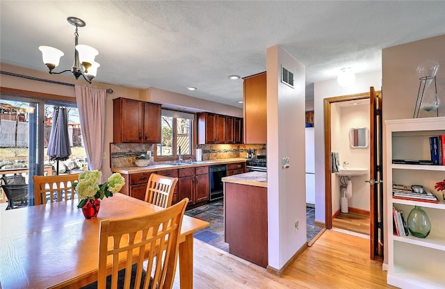 kitchen with light wood finished floors, visible vents, tasteful backsplash, light countertops, and black dishwasher