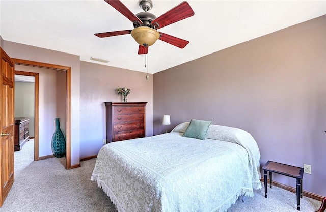 bedroom with ceiling fan, light colored carpet, visible vents, and baseboards