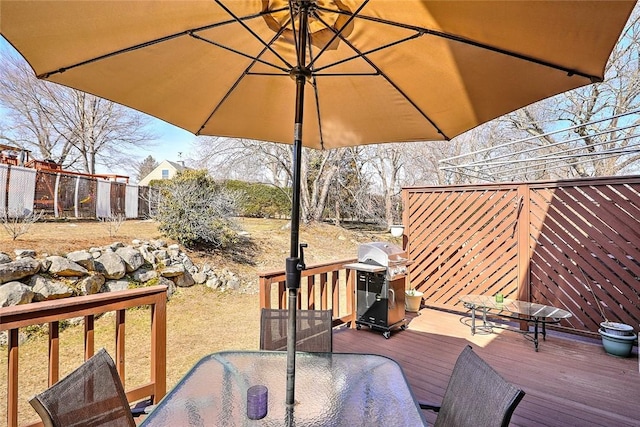 wooden terrace with outdoor dining area, fence, and grilling area