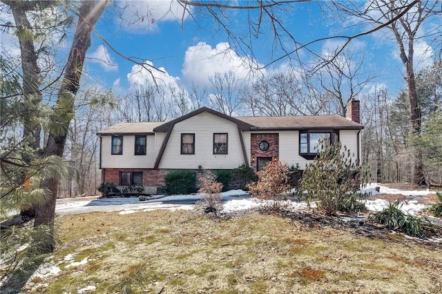 view of front of house with brick siding, a gambrel roof, and a chimney