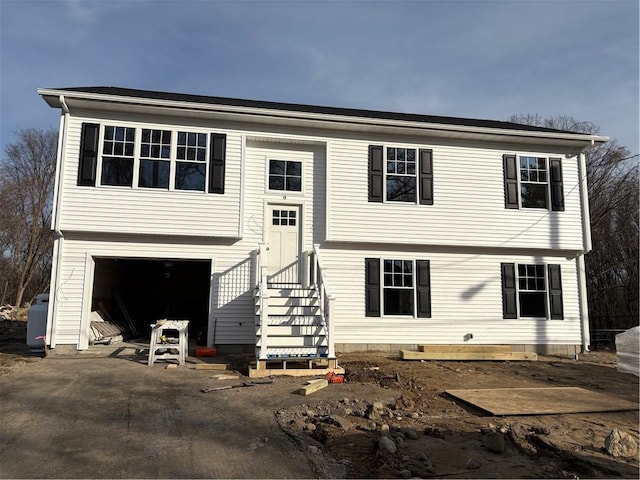 raised ranch featuring aphalt driveway and an attached garage