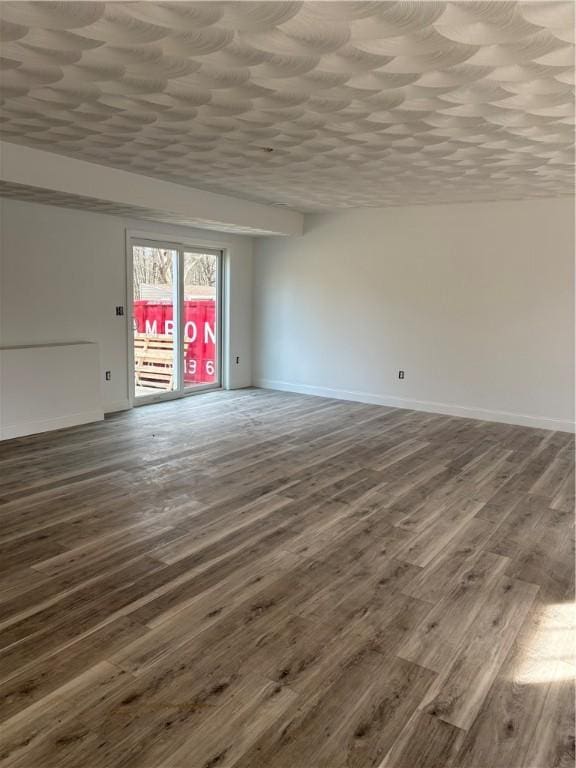 spare room featuring wood finished floors, baseboards, and a textured ceiling