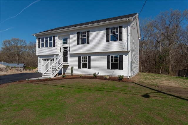 raised ranch featuring driveway, a front lawn, and a garage