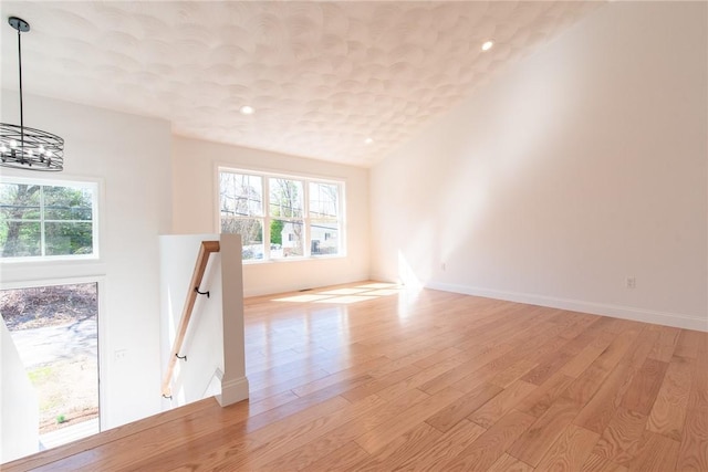 unfurnished room with recessed lighting, a notable chandelier, a wealth of natural light, and light wood-type flooring