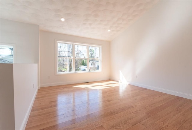empty room featuring recessed lighting, baseboards, and light wood-type flooring
